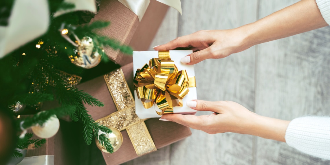 Photo of woman placing a gift box near a tree.