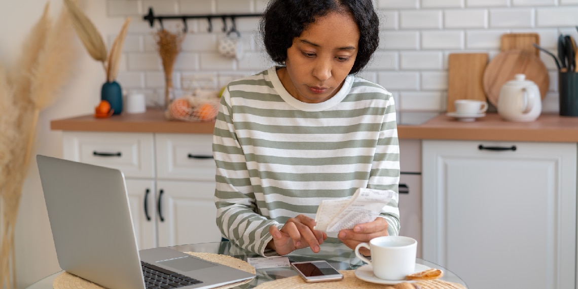 Photo of a woman reviewing her budget with a calculator.