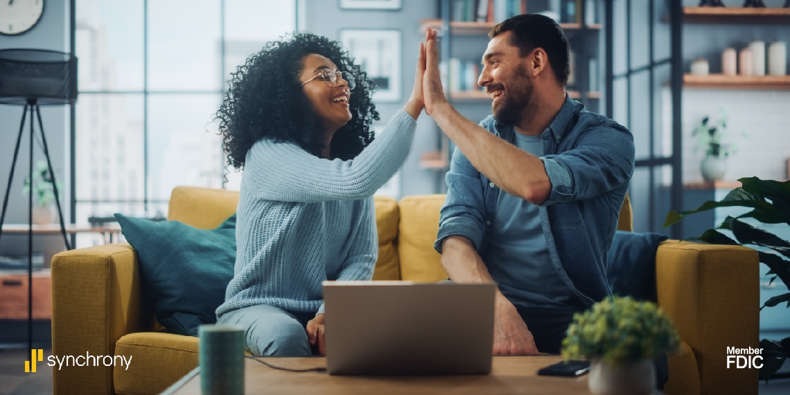 Photo of couple giving each other a high five on a couch.