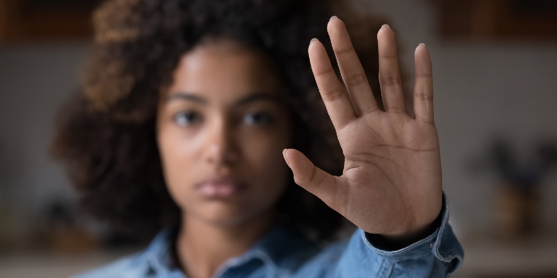 Photo of young African American woman raising her hand to say say stop or to halt.