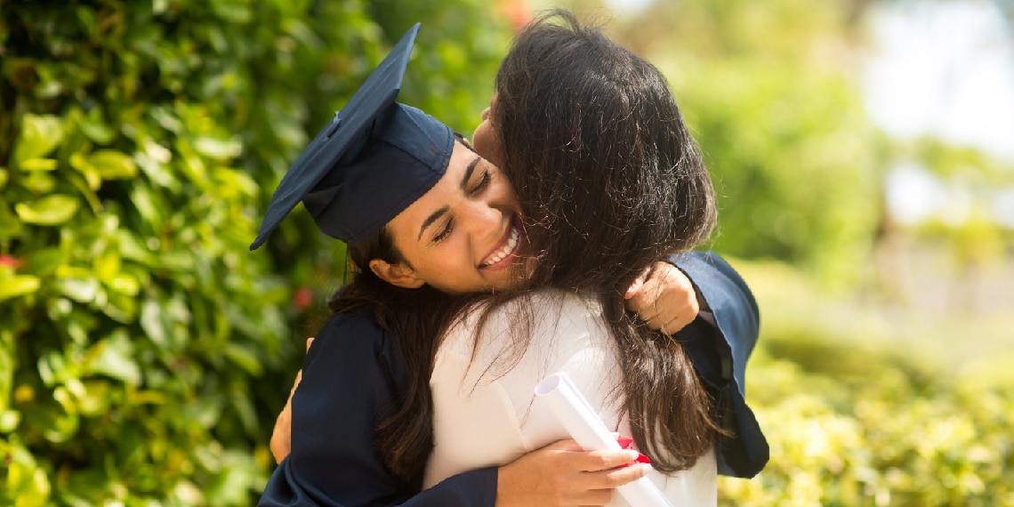 Female school graduate hugging another woman.