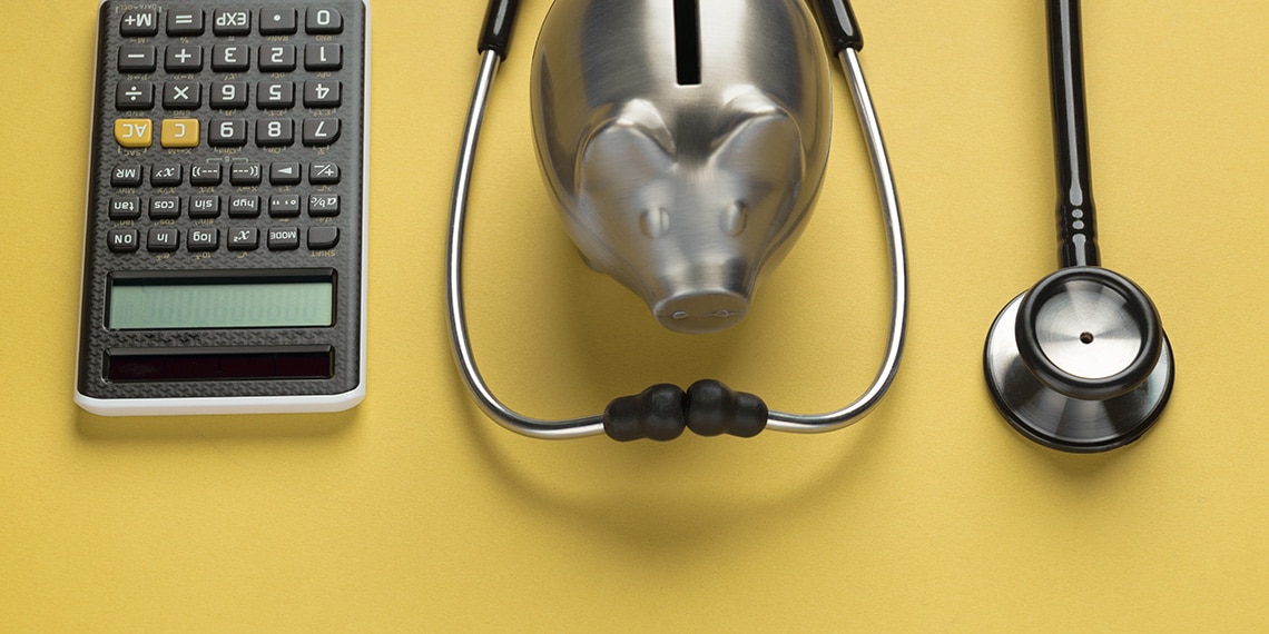 Piggy bank surrounded by a stethoscope and calculator.