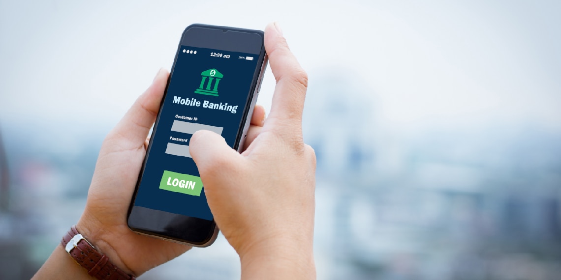 Photo of a hand holding a phone with a mobile banking app on the screen.