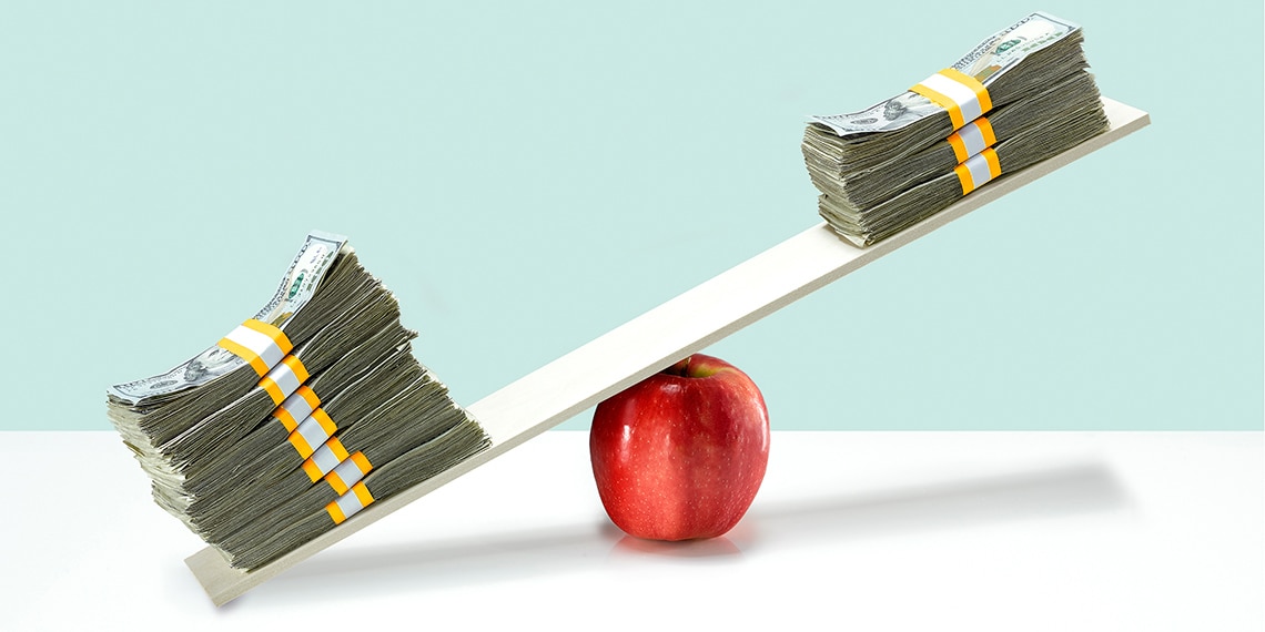 A scale with stacks of money balancing on an apple