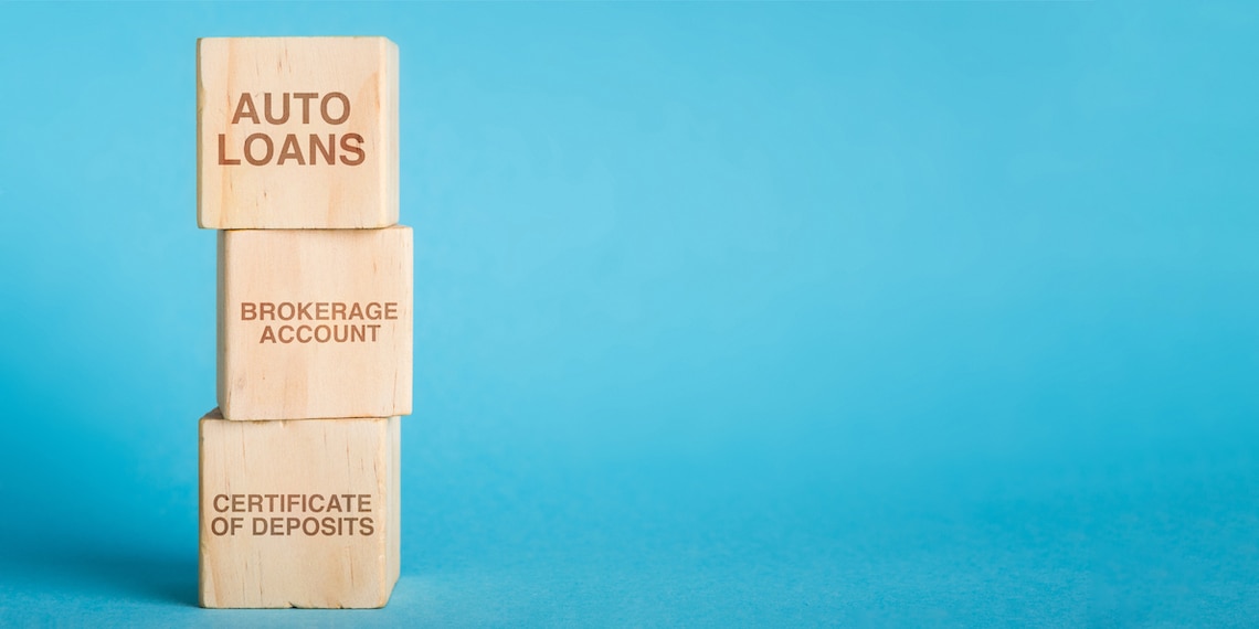 Photo of wooden blocks stacked on each other. The read “Auto Loans,” “Brokerage Account” and “Certificate of Deposits.”