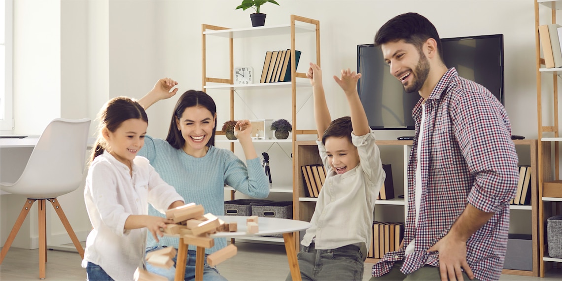 Picture of family excited and laughing playing a table game.