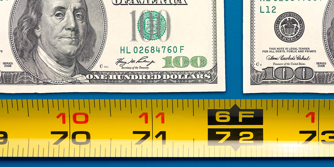 A measuring tape under hundred dollar bills.