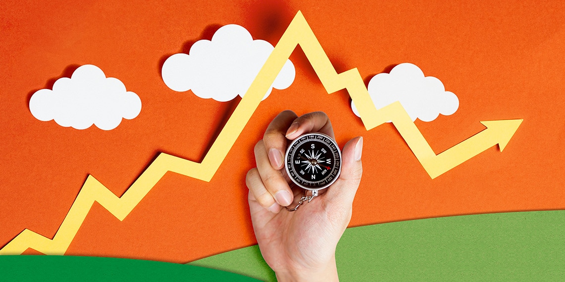 Image of a hand holding a compass beneath a market line chart.